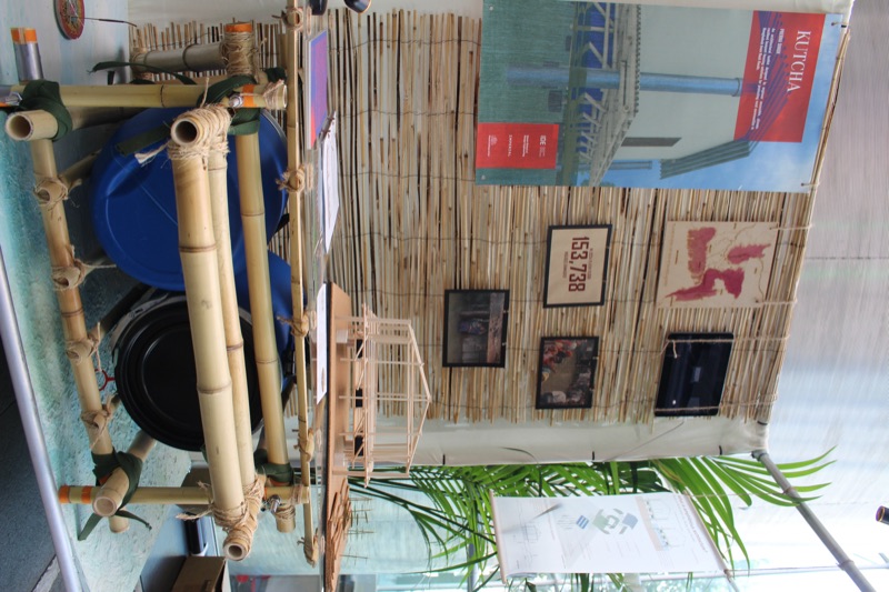 Exhibition stand with a bamboo and barrel raft, a model of the house and framed prints