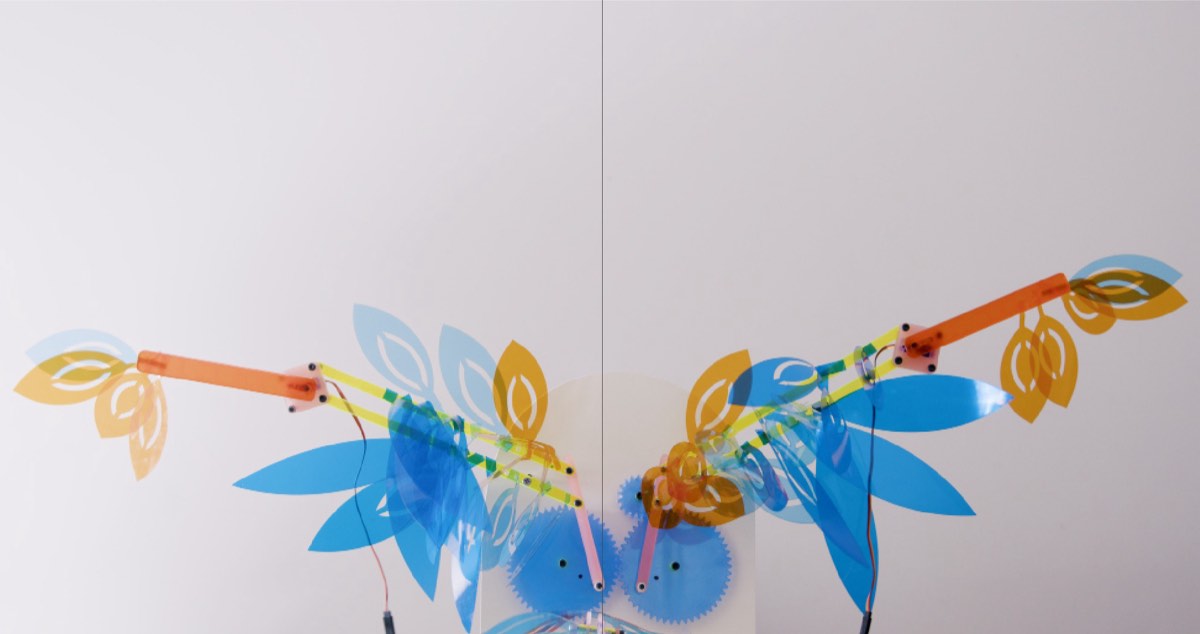 Kinetic sculpture with blue and orange leaf-shaped blades on two arms
